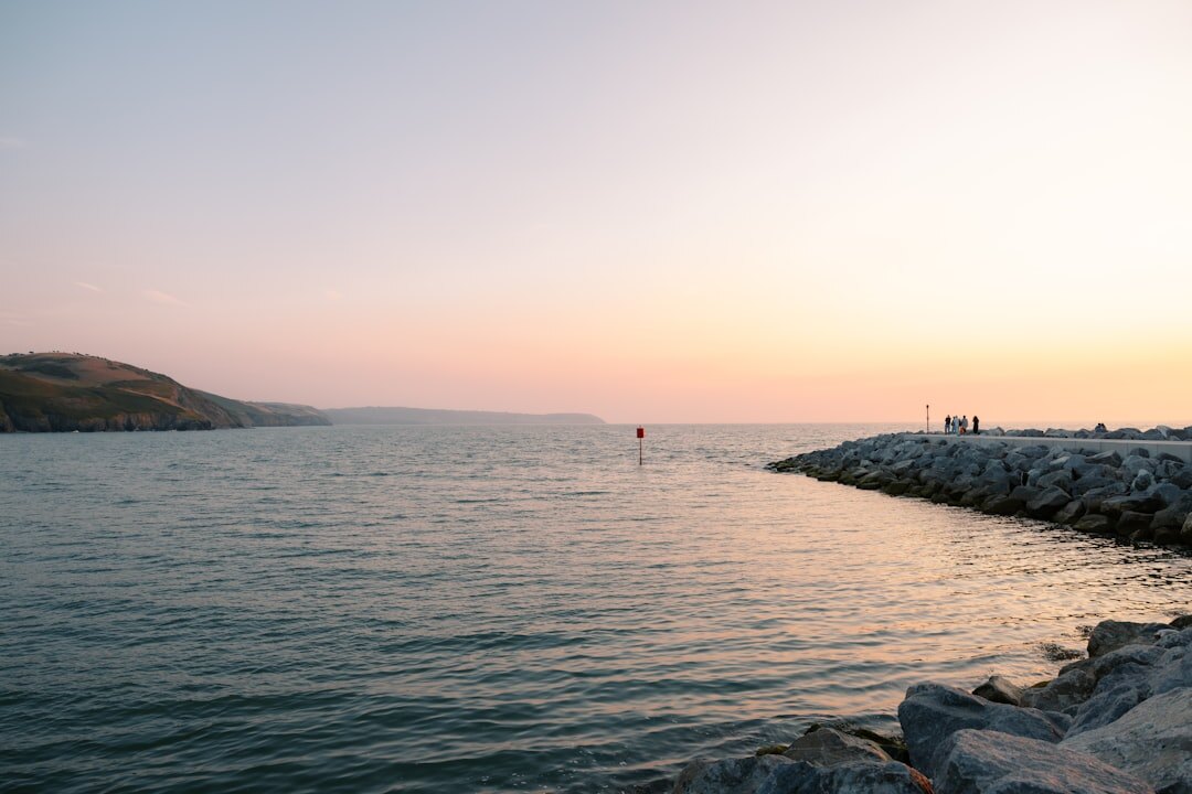 Fisherman untangling nets on stone pier at dawn