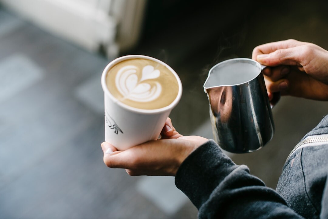 Barista pouring latte art in small coastal cafe
