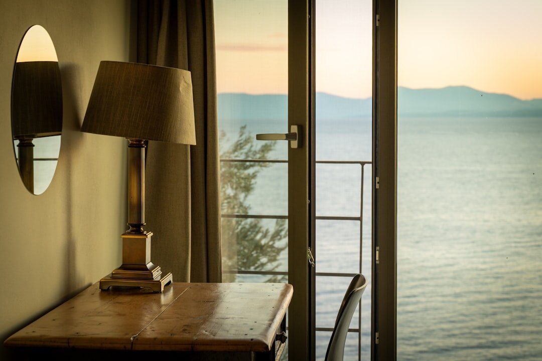 Camera and notebook on desk near window with sea view